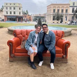 Darwin and Jennifer Gutierrez, DGSOM alumni who fell in loving during medical school, posing on an orange couch 