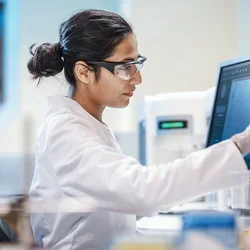 Female scientist in safety glasses working on a digital screen