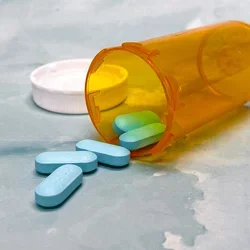 Blue pills spilling out of pill bottle