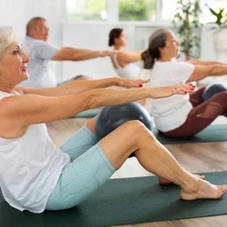 Individuals on mats completing yoga poses 