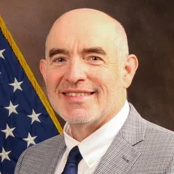 Steven Simon standing in front of a US flag