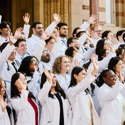 DGSOM’s class of 2030 waving and smiling candidly in front of UCLA’s Royce Hall.