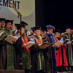: Award-winners Jessica B. O'Connell, MD (front row, third from the left) and Kat-Kit Hui, MD (front row, fourth from the left) join graduating doctors in reciting the Oath of Hippocrates at the 2026 commencement ceremony.