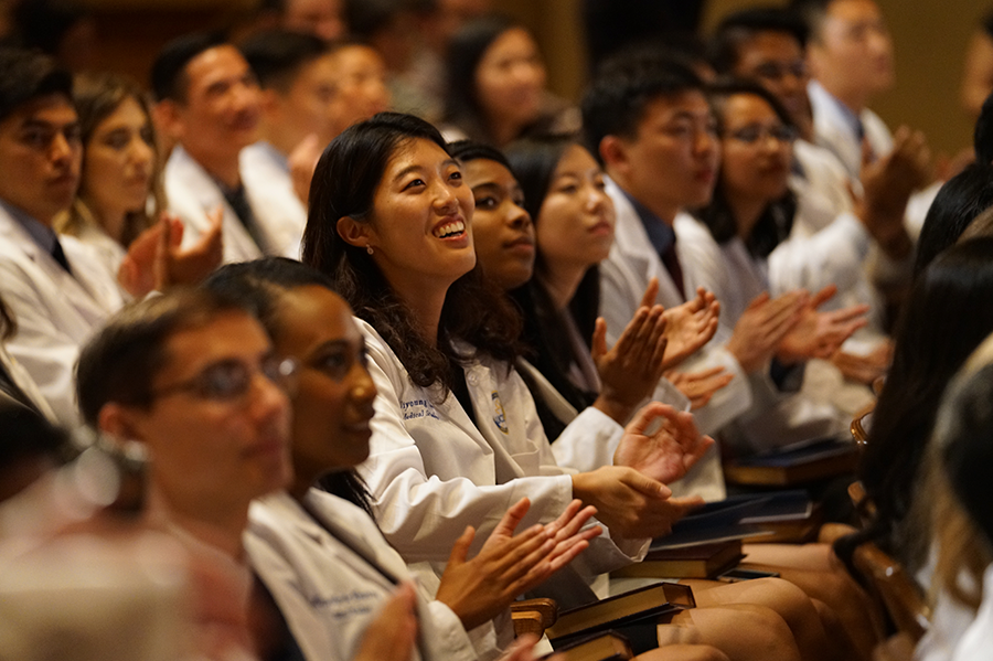 Rows of medical students in a lecture hall, clapping.