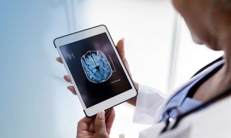 How Is Alzheimer's Diagnosed Doctor Looking at Brain Imaging on Tablet