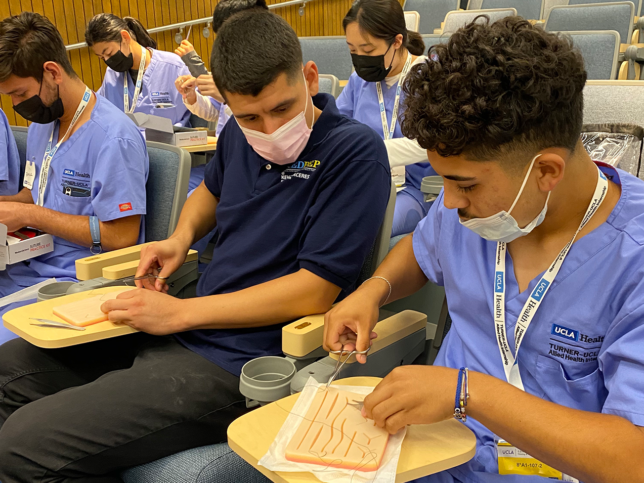 Kevin Caceres, UCLA MEDPEP Peer Mentor, teaching a high school student how to suture. 