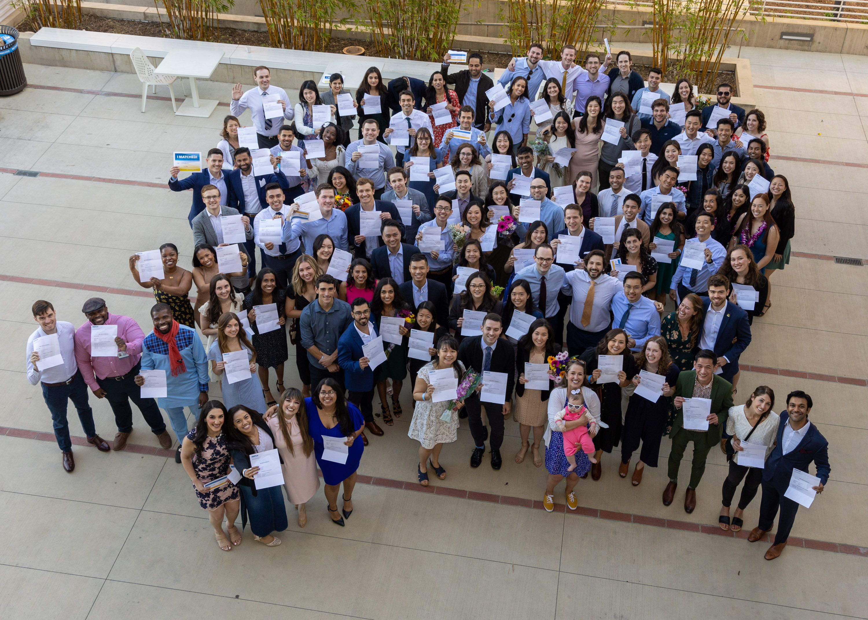 Medical Students matching stand in a courtyard together holding their match letters up with big smiles.
