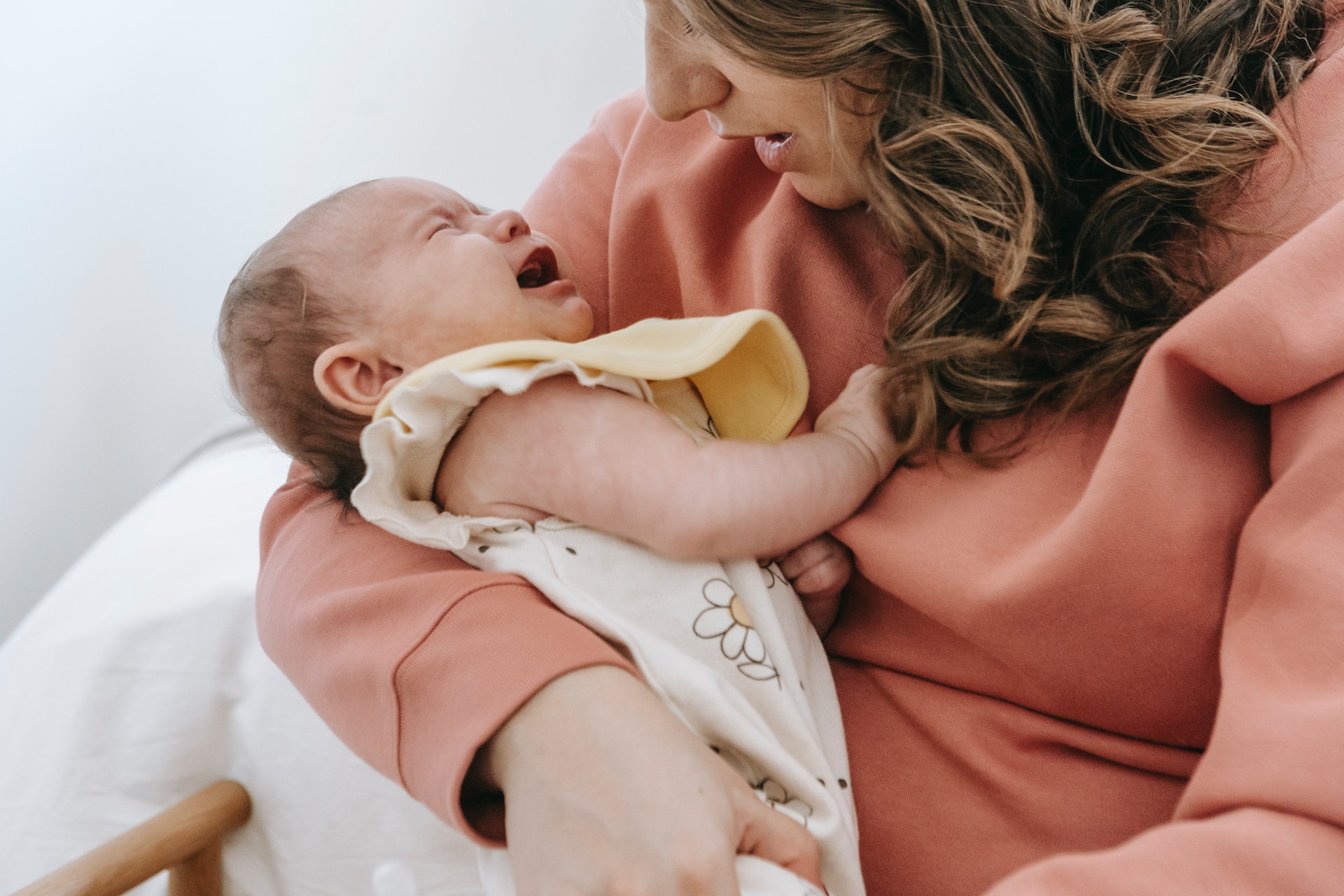 Baby crying in mother's arms depicting a common breastfeeding challenge