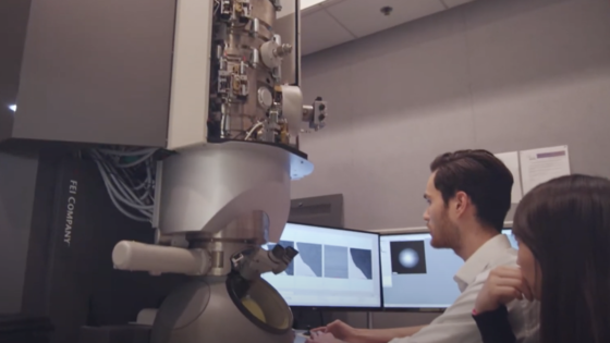 Two researchers review data on the screen of a large, powerful microscope"
