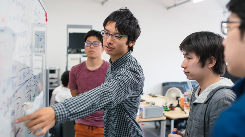 Human Genetics student in a classroom pointing at a white board in front of three other students