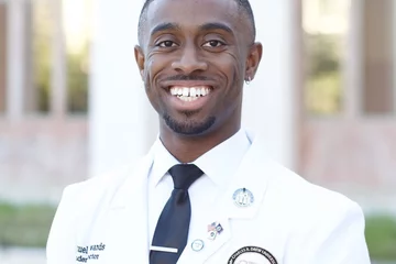 Medical student Samuel Edwards posing in his white coat