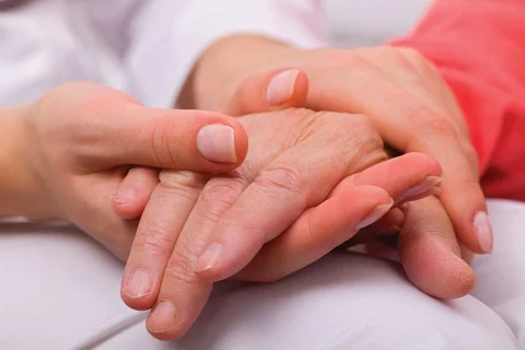 Alzheimer's Vs Dementia Closeup of Younger Caregiver Gently Holding Hands With a Senior Patient