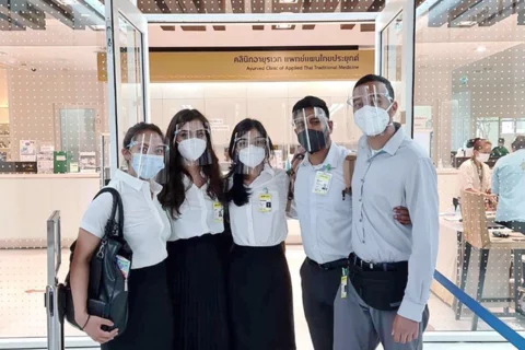 Studying Medicine Abroad A group of medical students, masked and with face shields, in front of a clinic of applied Thai traditional medicine