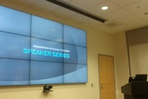 Screen in front of a room displaying "Speaker Series" in all caps