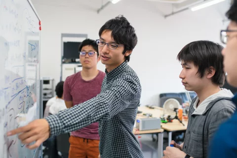 Human Genetics student in a classroom pointing at a white board in front of three other students