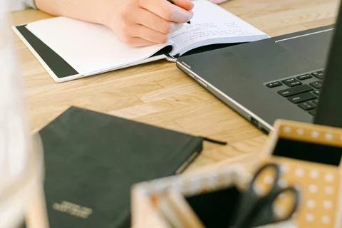 Person taking notes in front of computer.