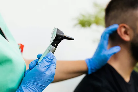person holding heine otoscope