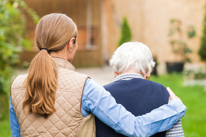 What Causes Dementia Younger Woman Walking With Arm Around Shoulders of Senior Patient