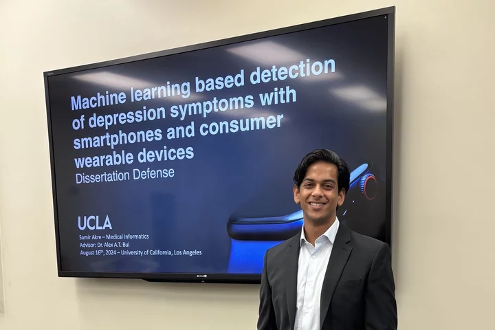 UCLA’s first medical informatics PhD, Samir Akre, pictured here standing in front of the title screen for his dissertation defense.