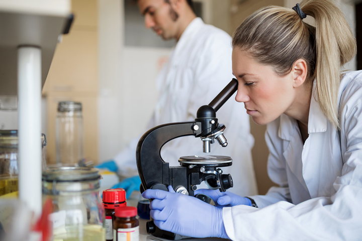 Woman in a lab coat looking into a microscope