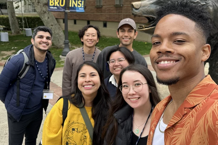 Medical student Laz Curry standing with several other people in front of UCLA’s famous Bruin bear statue.