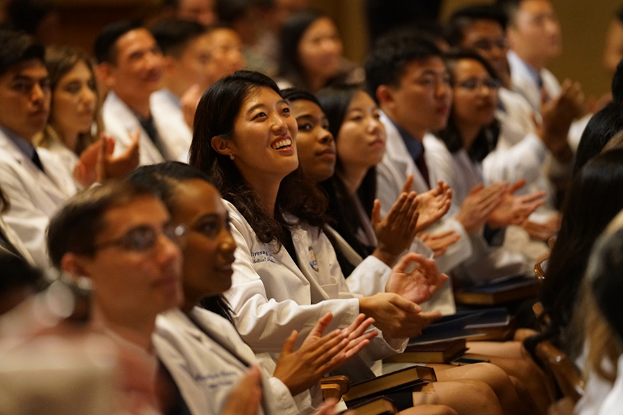 Rows of medical students in a lecture hall, clapping.
