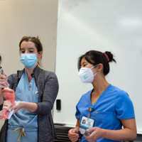 Med School Mentorship Program A group of medical students, all women, work on a problem together in a simulation lab