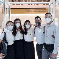 Studying Medicine Abroad A group of medical students, masked and with face shields, in front of a clinic of applied Thai traditional medicine