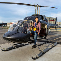 Xin Qi posting in front of a helicopter