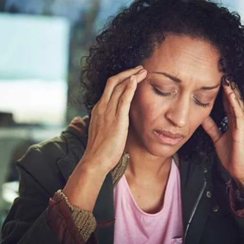 Woman with a migraine rubbing her temples