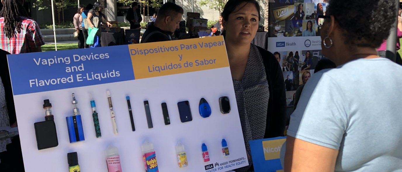 How to Prevent Cancer Via Lifestyle Choices. People review information on vaping at a health fair