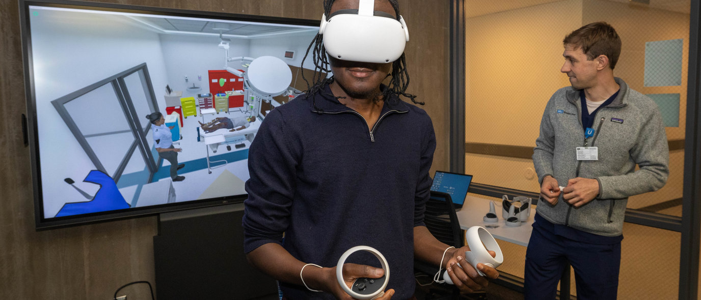 Anesthesiology administrative specialist Jibril Osumanu, left, wears a VR headset for an immersive 3D medical simulation scenario alongside Daniel Weisman, simulation center learning experience designer and station facilitator.