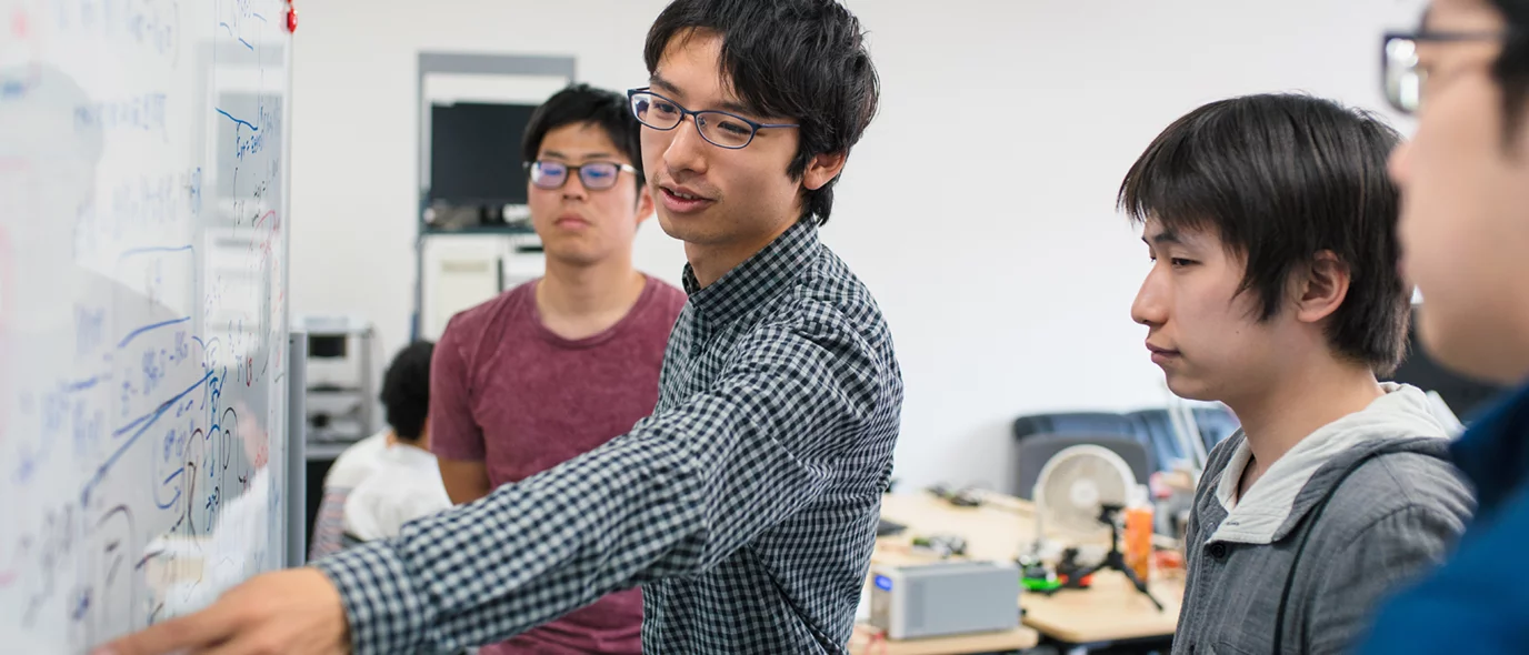 Human Genetics student in a classroom pointing at a white board in front of three other students