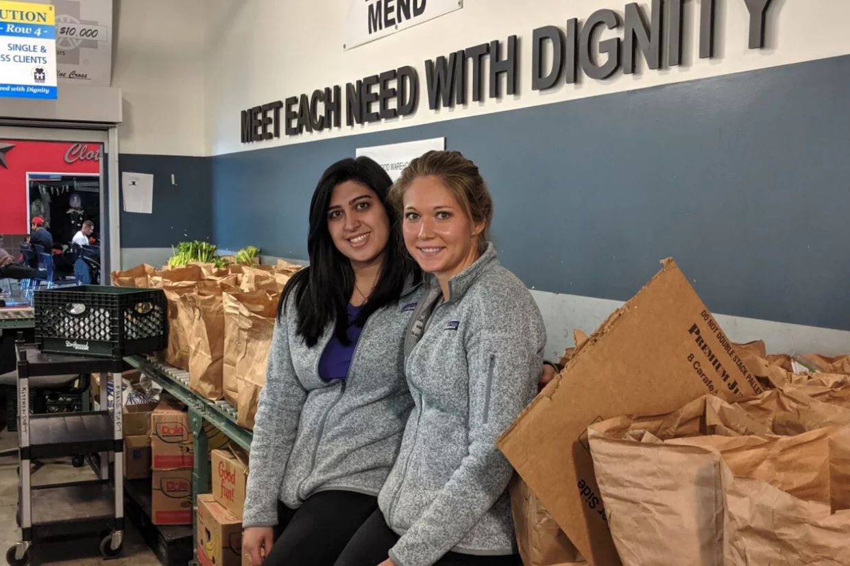 Meeting the needs of the community through compassionate care, two students at a local food bank