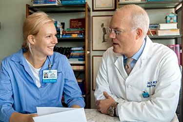 Two medical professionals talking at a table with documents