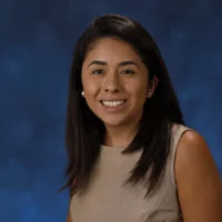 Andrea Martinez smiling portrait in front of blue backdrop