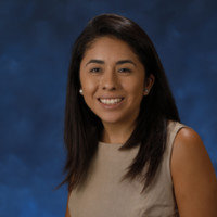 Andrea Martinez smiling portrait in front of blue backdrop