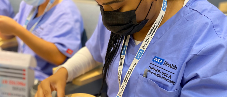 Harmony Taylor from the Turner-UCLA Allied Health Internship Program in Summer 2022 practicing surgical technician tasks including a mock suturing exercise.