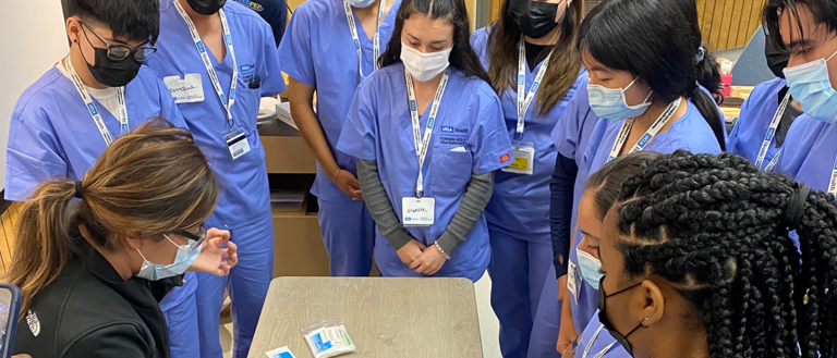 Lizbeth Sanchez Olivera UCLA MEDPEP Mentor teaching students how to use the suturing equipment. 