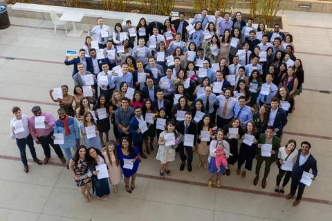 Medical Students matching stand in a courtyard together holding their match letters up with big smiles.