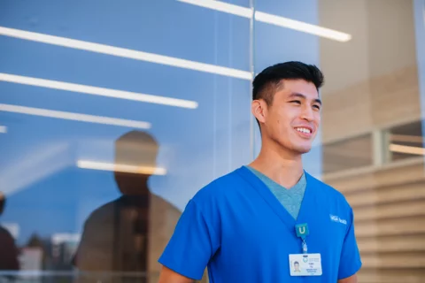 UCLA medical school resident stands outside of the Center for Health Sciences with a smile on his face.