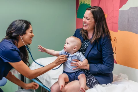 UCLA Medical School Student Doctor Providing Patient Care to Mother With Baby on Lap